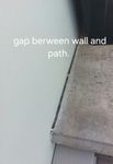 gap has tape between wall and path on both house and fence side.