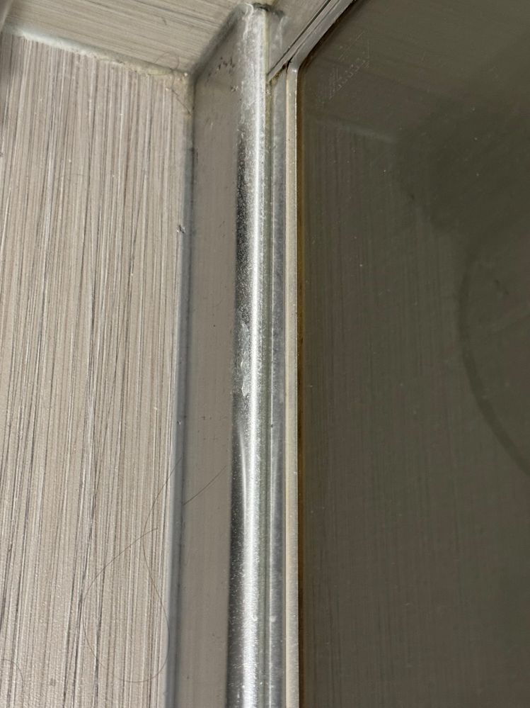 Outside of the shower area, next to wear the gap is