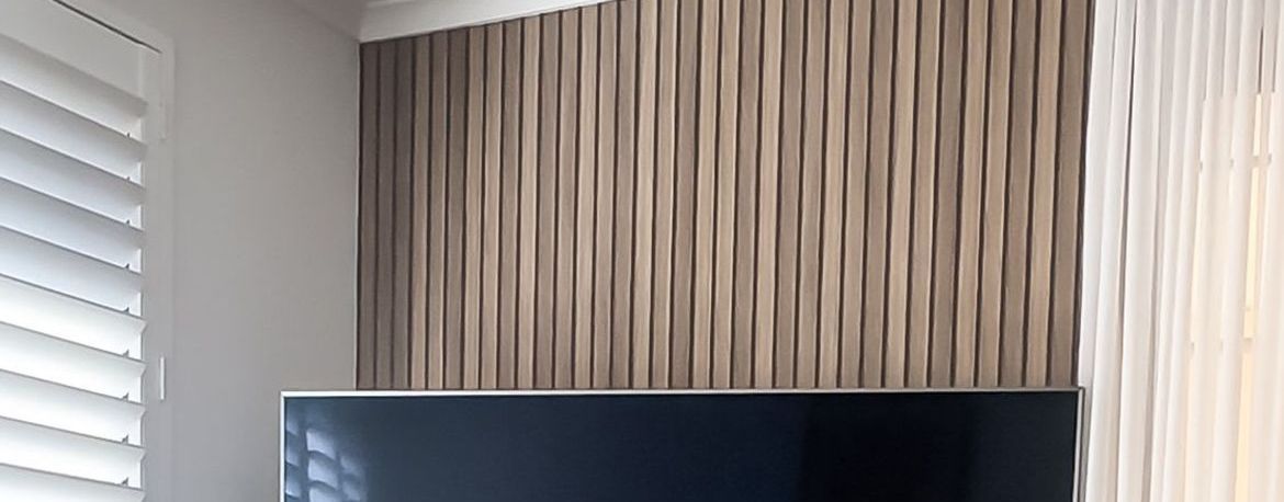 Wall-mounted television with wood panel wallpaper.JPG