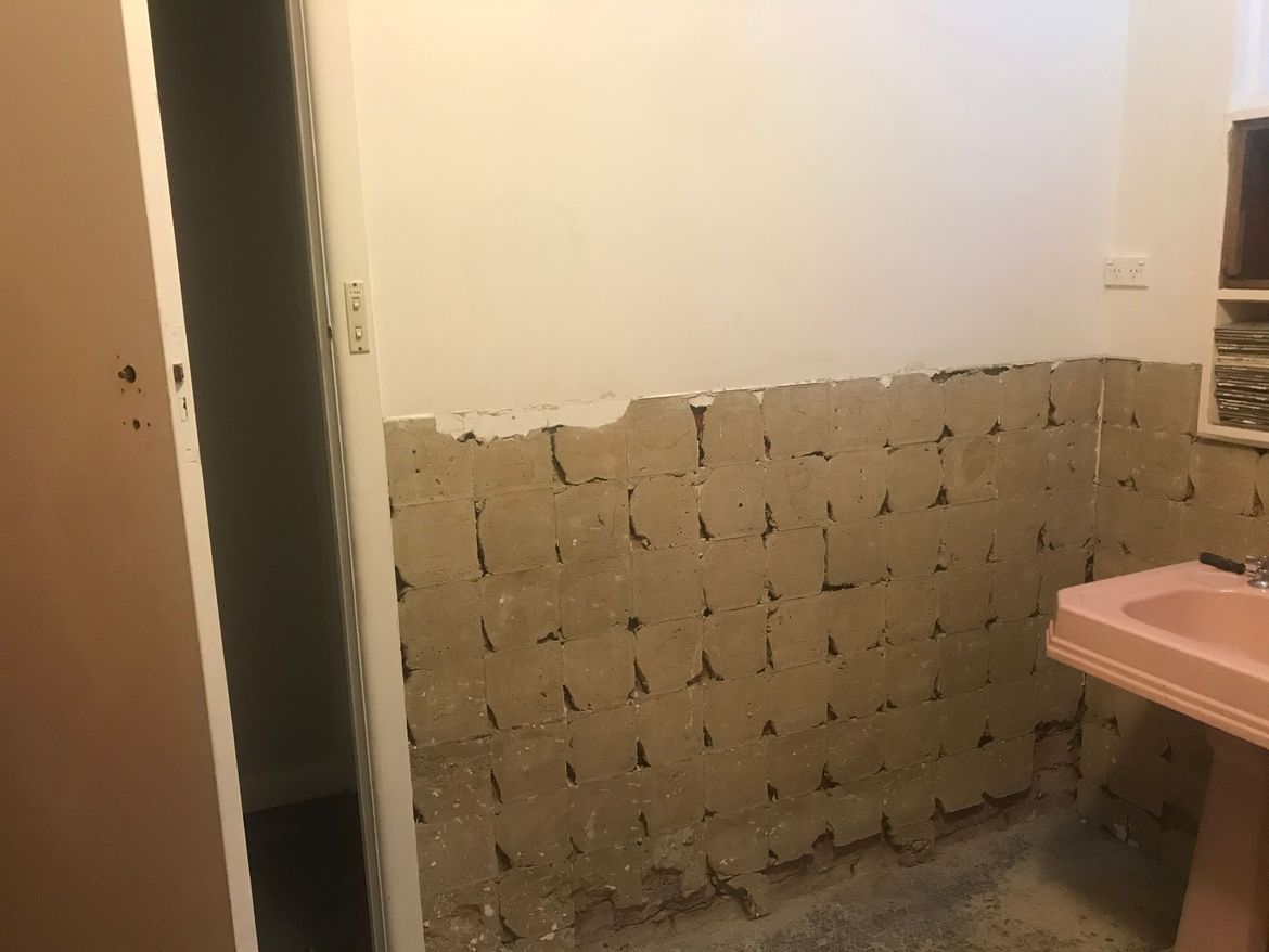 Wall needs to be tiled, but this render is not even and needs to be grounded somewhat. It is more raised than the plaster and thicker at the bottom.