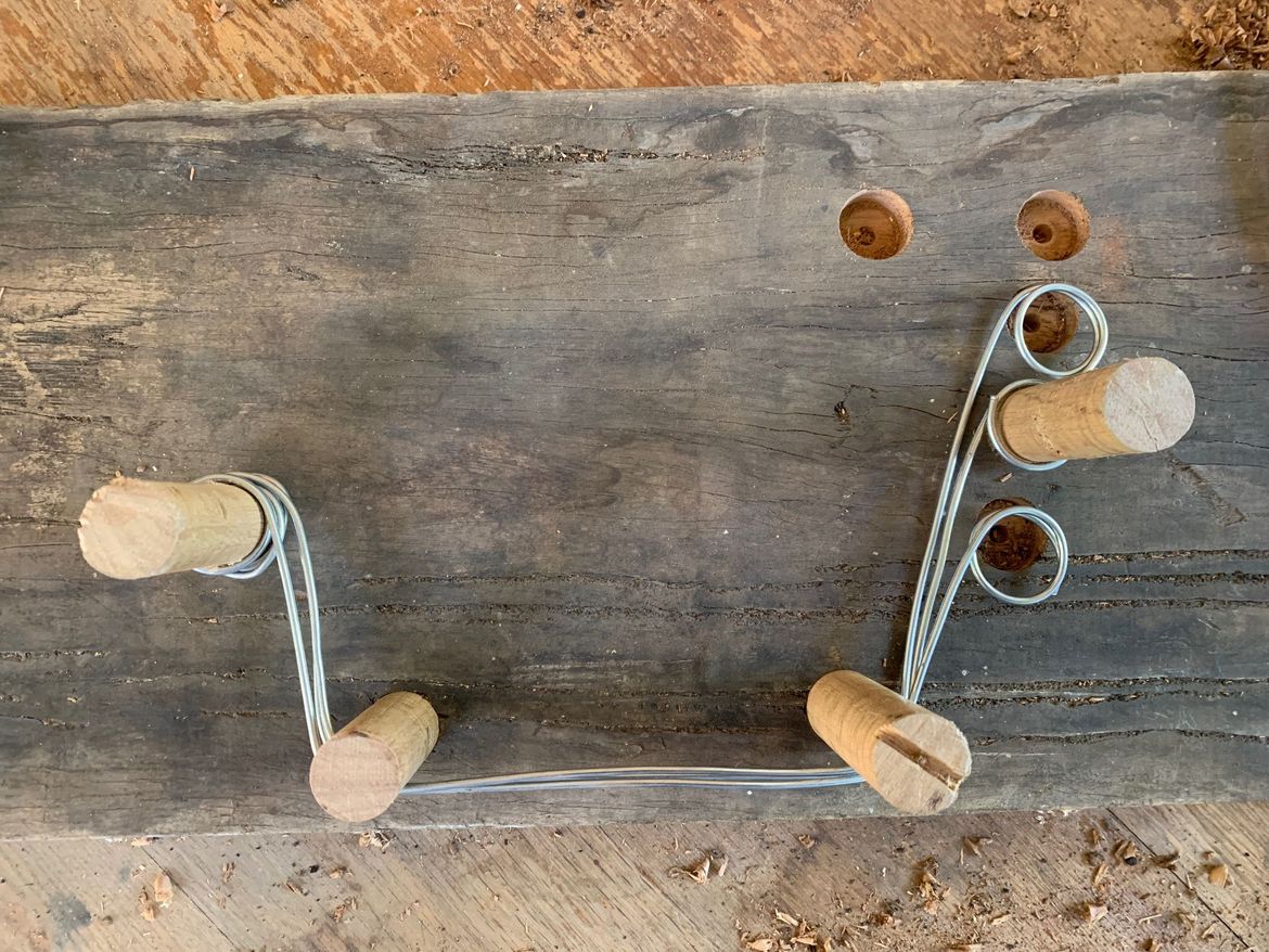 Bending the wire segments. After bending the wire with pliers, it was found that the lengths wouldn't be the same. Hence, here, 22mm holes have been drilled with a spade bit, and 22mm dowel used. The segents will be the right lengths.