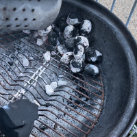 4.a Place lit charcoal on one side of the barbecue.png