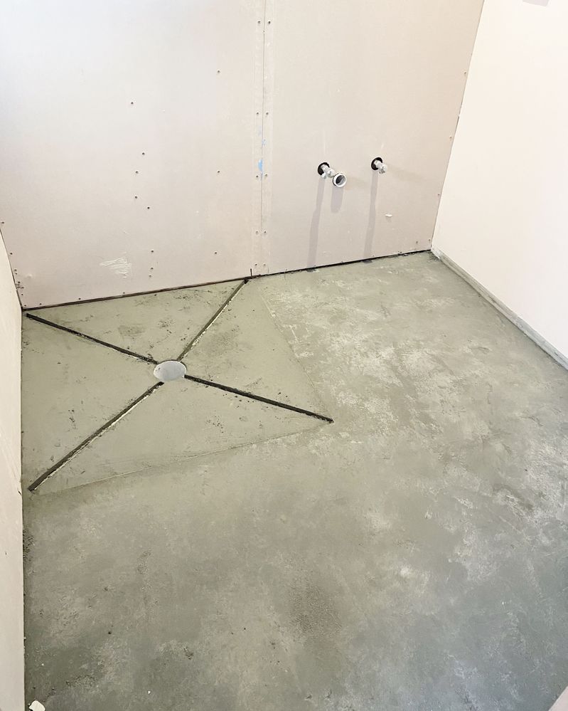 Bonded screed laid to raise floor level to allow for falls to waste in shower.