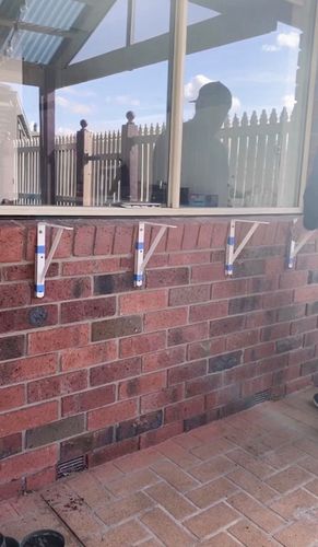 Spacing our the brackets, using timber wedges against the brick ledge and checking that all the brackets are level.