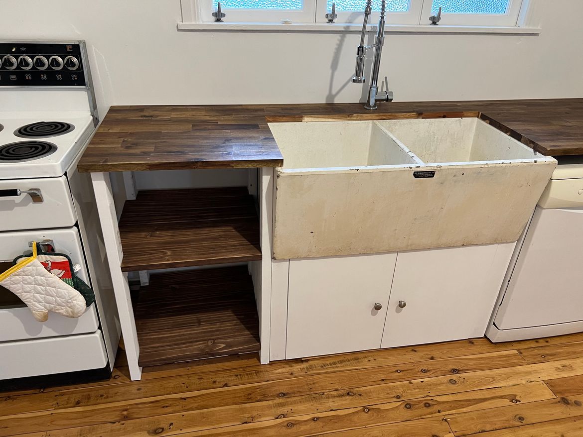 Finished kitchen bench with Bunnings counter, palette shelves, recycled sink, and DIY under sink storange