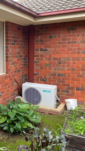 BEFORE: Old a/c condenser unit sitting on the ground with a brick edging