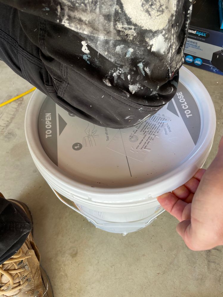 The easy way to get stubborn lids off plastic paint buckets! A knee firmly in the centre and peel one edge of the lid back.